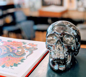 Chrome skull beside an open tattoo book