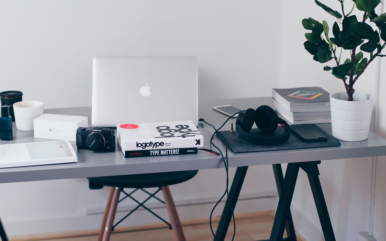 Desk with a laptop, books, a camera and headphones