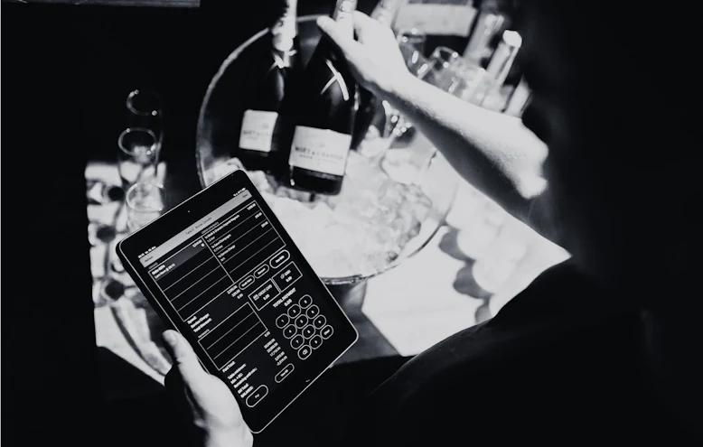 Employee holding an iPad running Nyx in a nightclub while serving champagne
